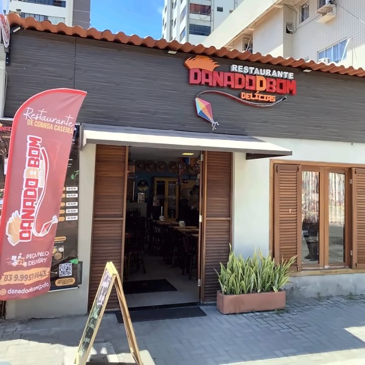 Fachada do Restaurante DanadoDBom com placa vermelha e bandeira na calçada