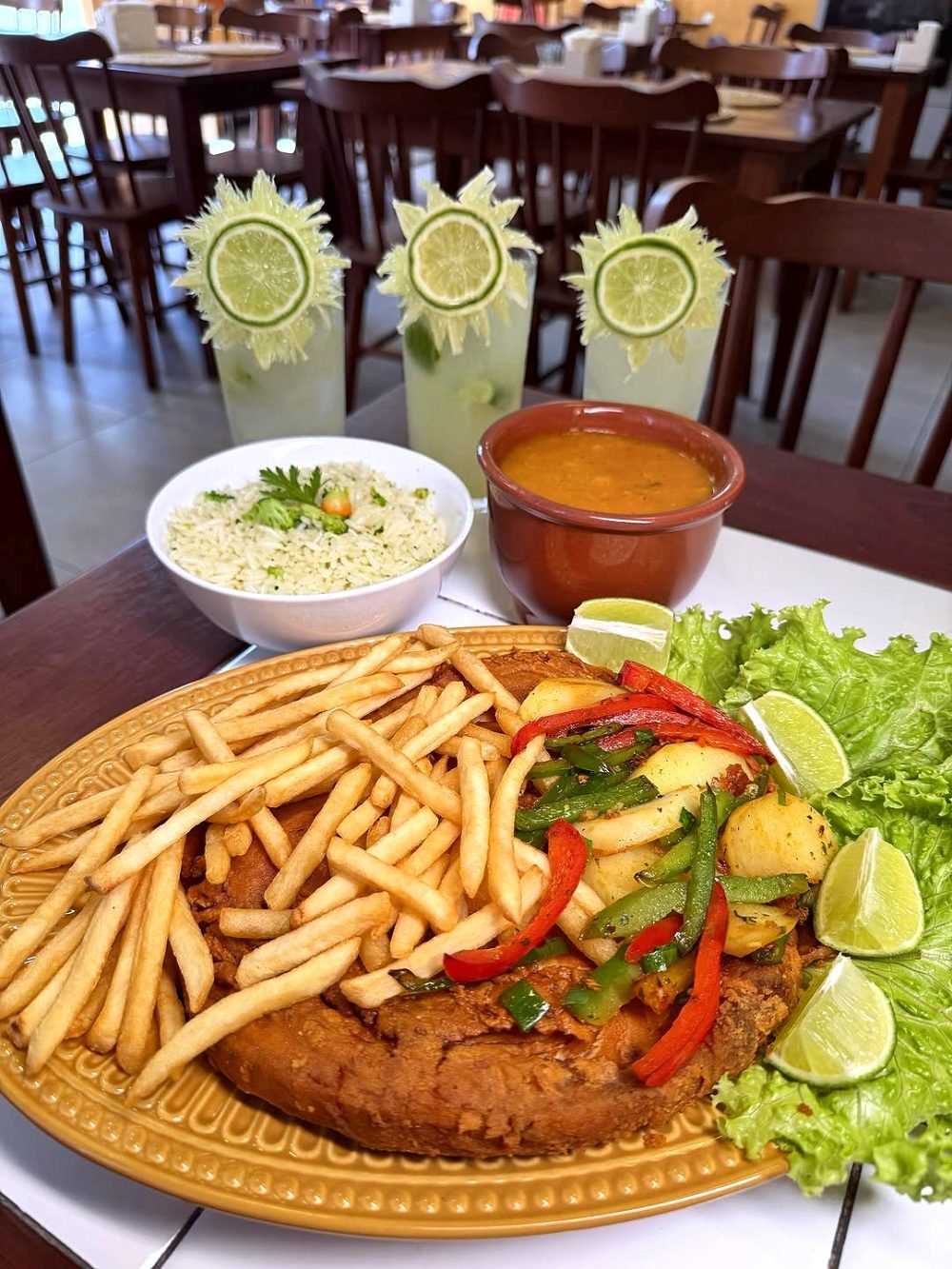 Posta de meca frita com batata, pimentões coloridos, salada e sucos de limão