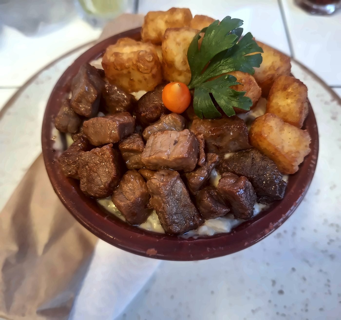 Rubacão na panelinha de barro sobre prato branco, com carne de sol e queijo coalho